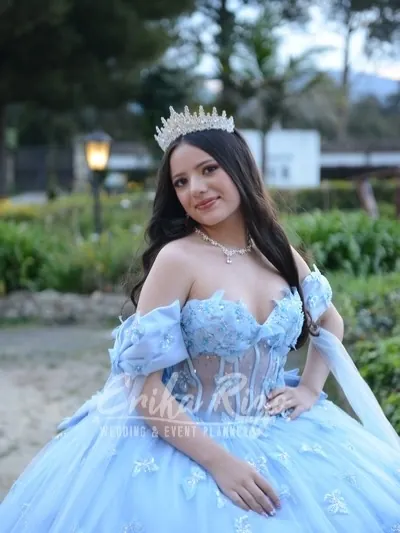 Quinceañera con vestido azul en los jardines